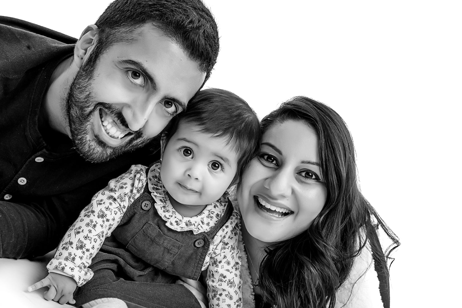Black and white photo with baby Deeya and her parents looking at camera all smiling