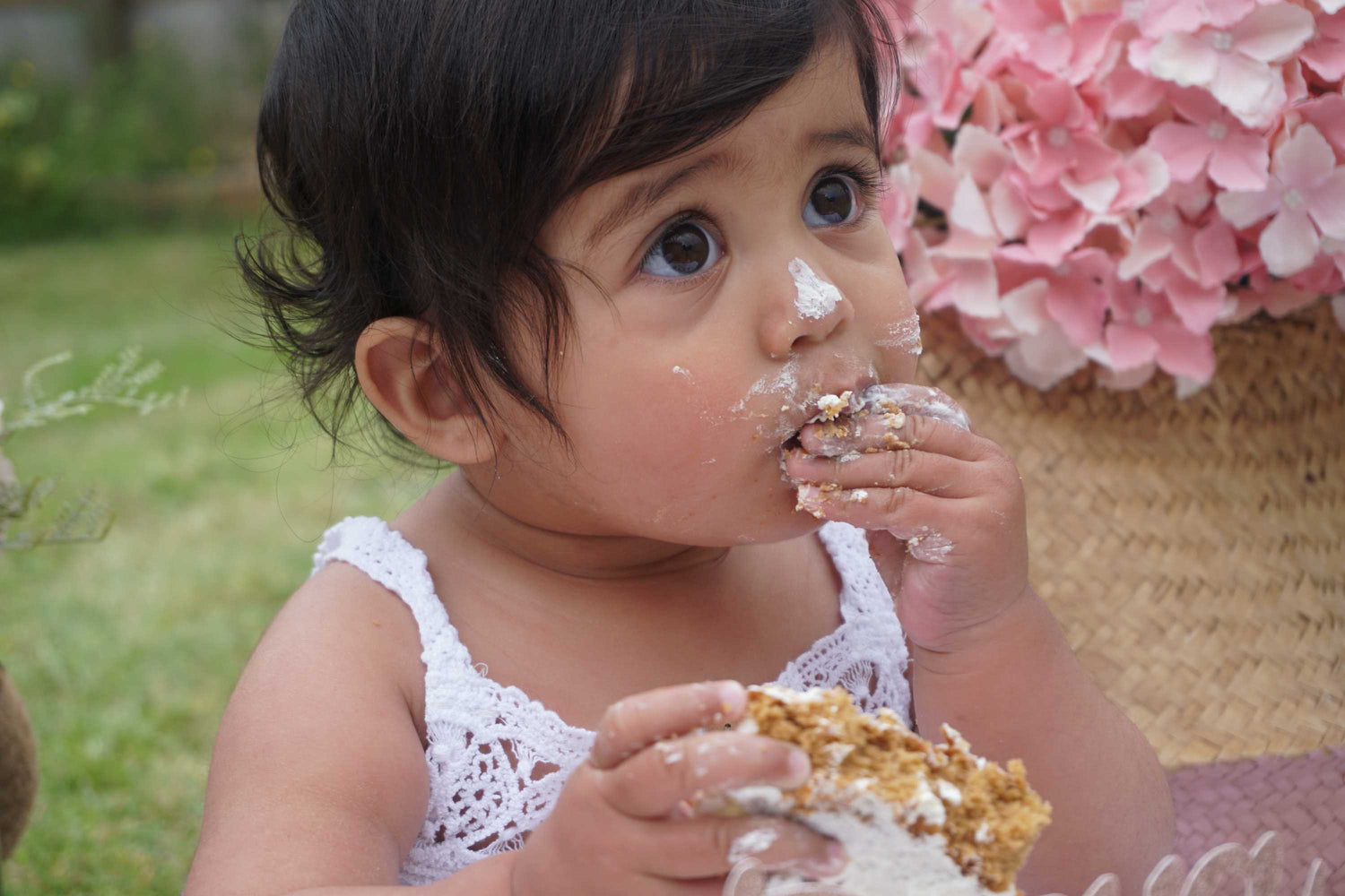 Baby Deeya eating cake with some cream from cake on her face and nose